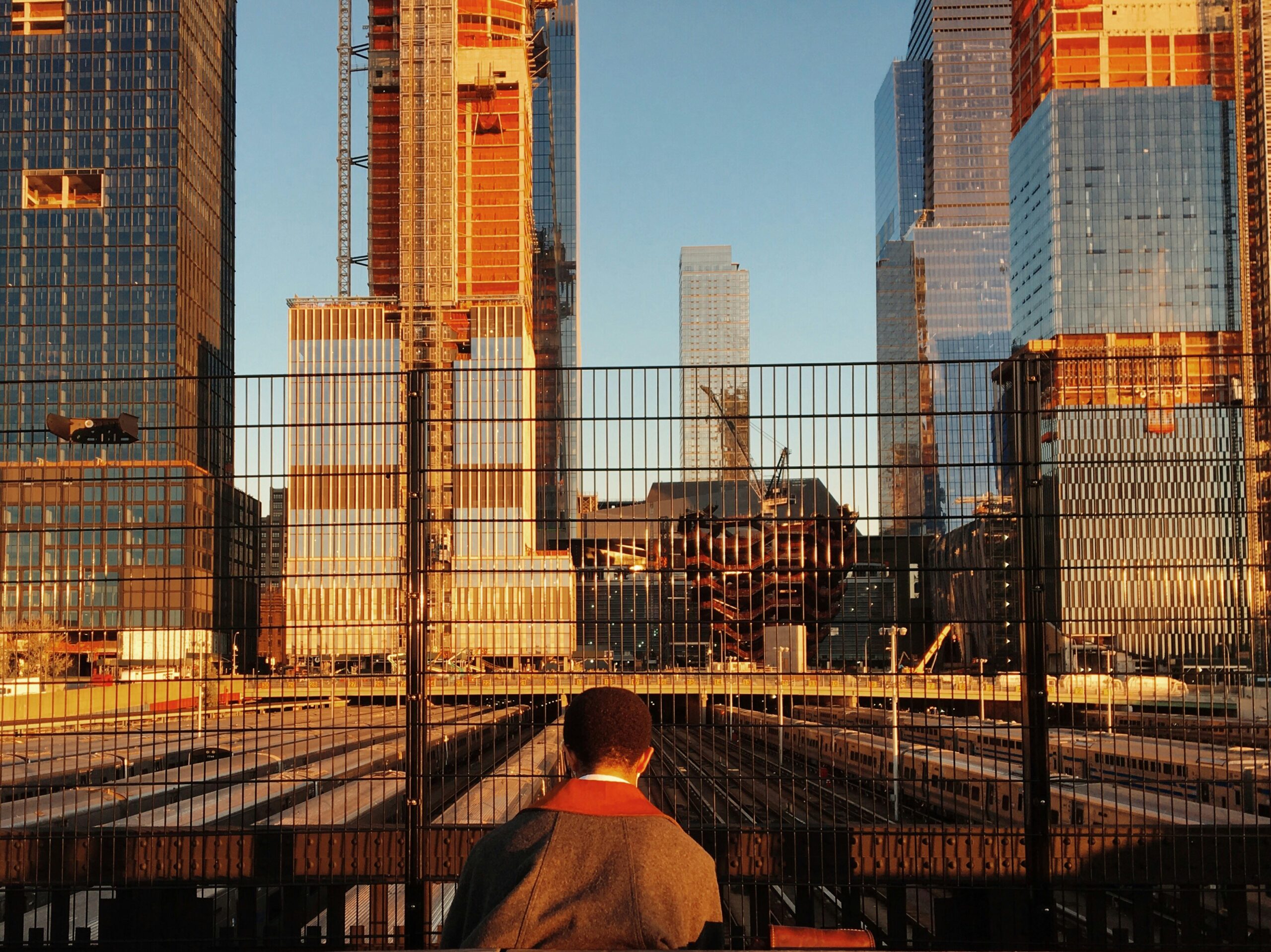 person facing gate and high-rise buildings